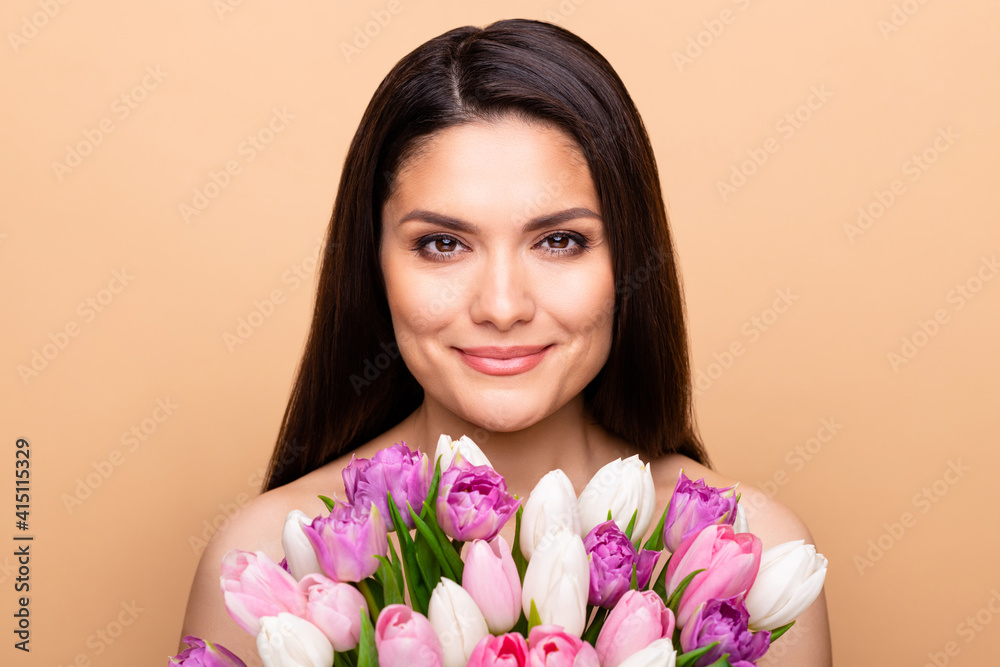 Portrait of nice optimistic brunette long hairdo lady hold flower without clothes isolated on pastel beige color background