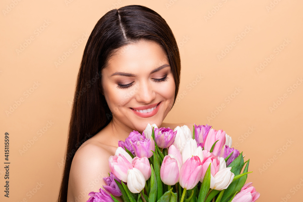 Portrait of nice optimistic brunette long hairdo lady hold look flower without clothes isolated on pastel beige color background Portrait of nice optimistic brunette long hairdo lady hold look flower without clothes isolated on pastel beige color background