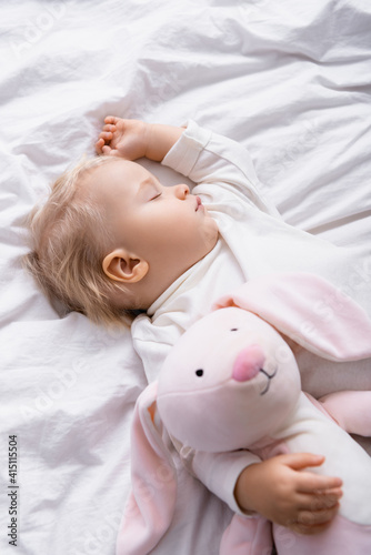 high angle view of baby boy sleeping with toy bunny at home