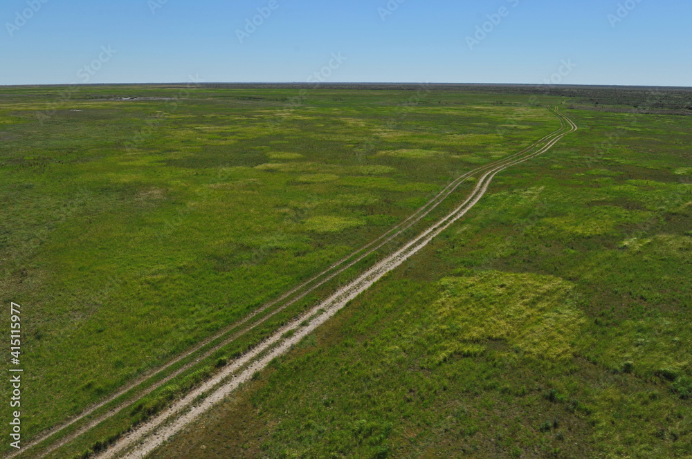 Zhambyl region, Kazakhstan - 05.17.2013 : The road runs along a wide valley with sandy and rocky ground, grass and shrubs