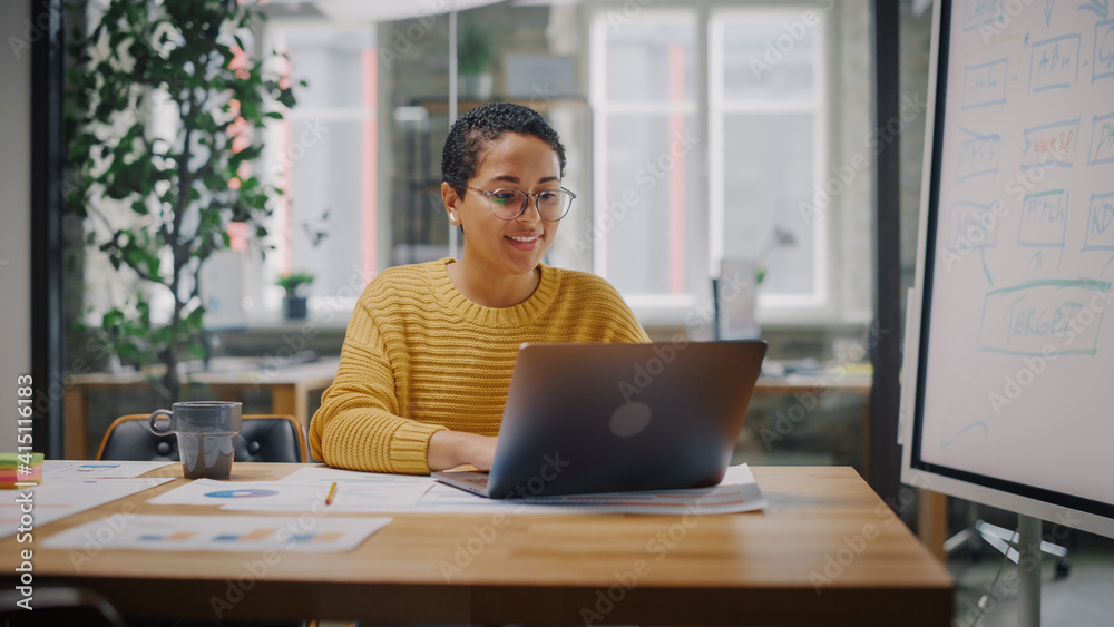 Portrait of Young Latin Marketing Specialist in Glasses Working on Laptop Computer in Busy Creative Office Environment. Beautiful Diverse Multiethnic Female Project Manager is Browsing Internet. Portrait of Young Latin Marketing Specialist in Glasses Working on Laptop Computer in Busy Creative Office Environment. Beautiful Diverse Multiethnic Female Project Manager is Browsing Internet.