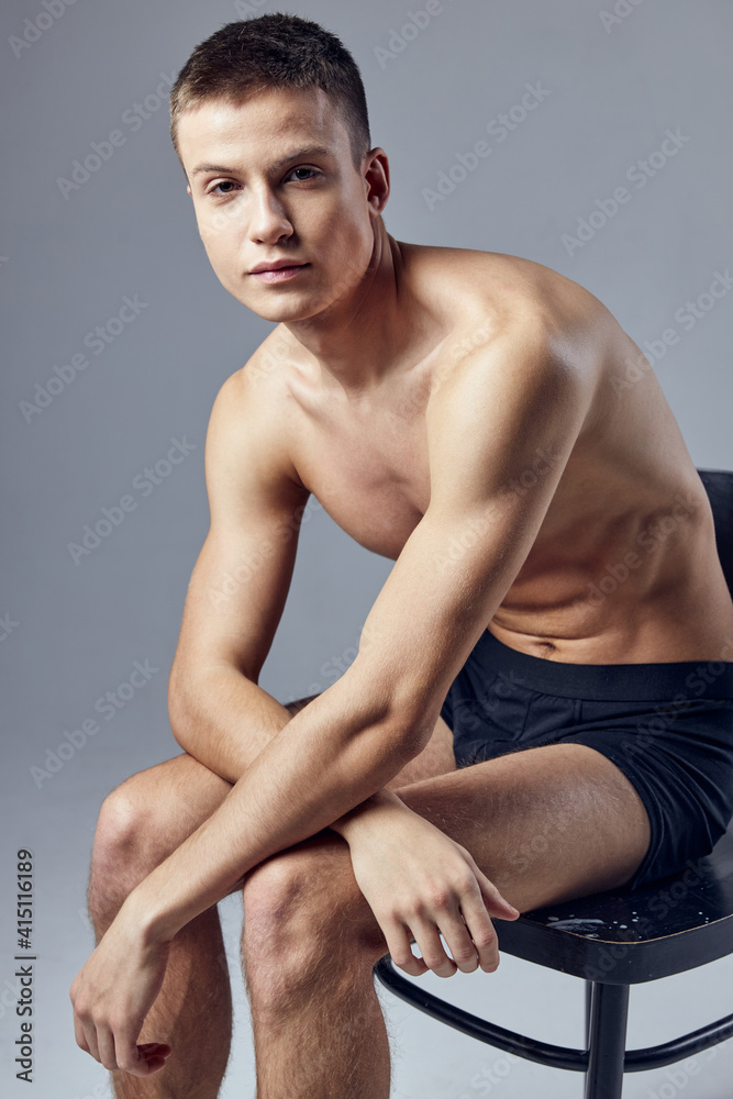 nice guy with a pumped up naked torso in black panties sits on a chair nice guy with a pumped up naked torso in black panties sits on a chair
