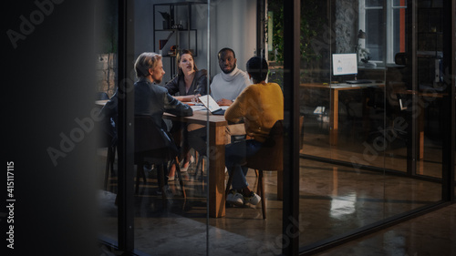 Young Creative Team Meeting with Business Partners in Conference Room Behind Glass Walls in Agency. Colleagues Sit Behind Conference Table and Discuss Business Opportunities, Growth and Development. © Gorodenkoff