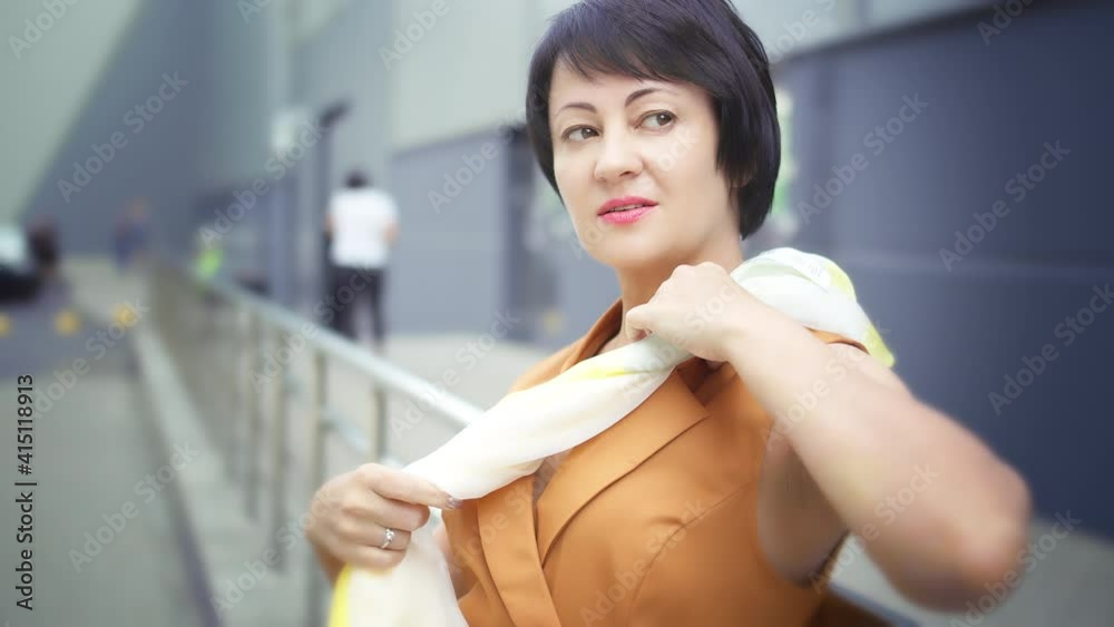 brunette woman playing with a scarf on the street and looking at the camera, stylish woman brunette woman playing with a scarf on the street and looking at the camera, stylish woman
