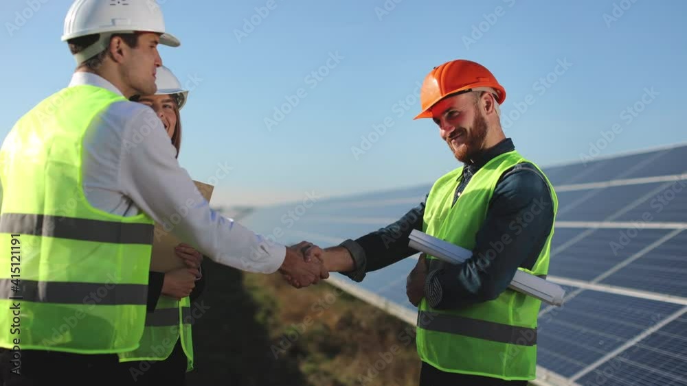 The engineer is greeting his colleagues. They are talking and standing next to solar panels. 4K. The engineer is greeting his colleagues. They are talking and standing next to solar panels. 4K.