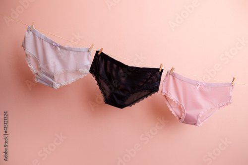 colorful clean women's panties hang on a rope. on a pink isolated background photo