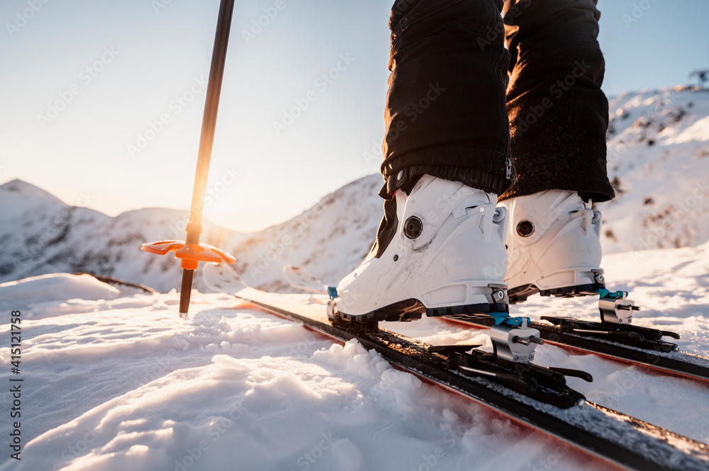 Mountaineer backcountry ski walking in the mountains. Ski touring in high alpine landscape. Adventure winter extreme sport. Detail boots. - obrazy, fototapety, plakaty 