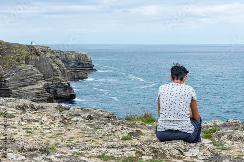 young woman from behind looking at the sea from a cliff