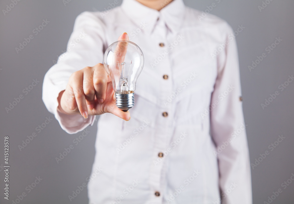 Woman hand holding a bulb. On a gray background. Woman hand holding a bulb. On a gray background.