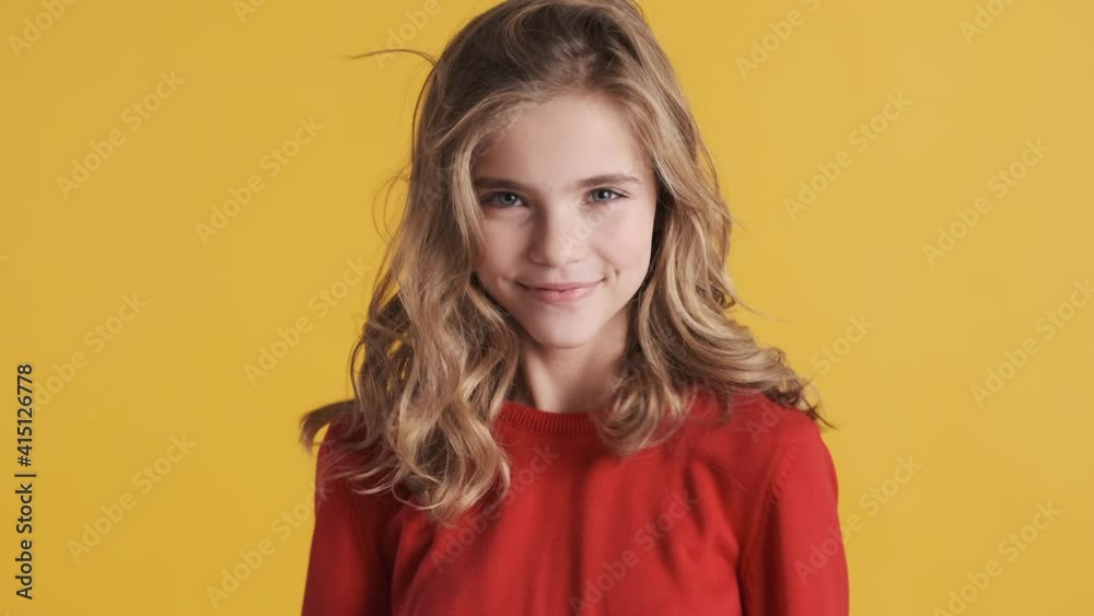 Pretty blond teenager girl dressed in red sweater dancing and smiling on camera over colorful background