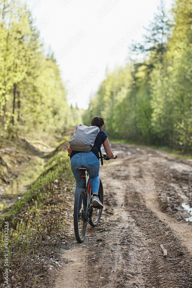 Obraz premium The female cyclist riding on her mountain bike on the forest path. Tires on the dirty forest road. Concept of choice mtb for riding on the loam.