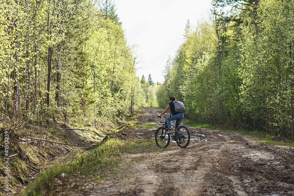 The female cyclist riding on her mountain bike on the forest path. Tires on the dirty forest road. Concept of choice mtb for riding on the loam.