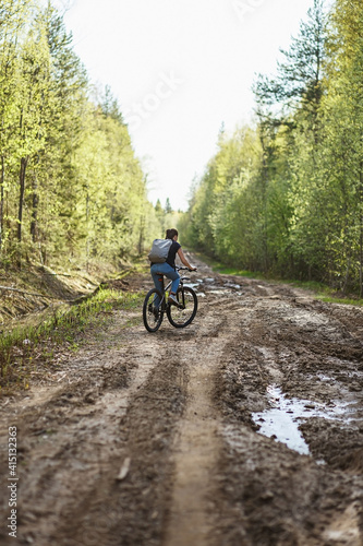 The female cyclist riding on her mountain bike on the forest path. Tires on the dirty forest road. Concept of choice mtb for riding on the loam. © Northern life