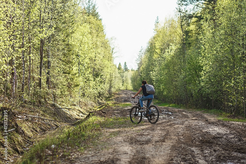 The female cyclist riding on her mountain bike on the forest path. Tires on the dirty forest road. Concept of choice mtb for riding on the loam.