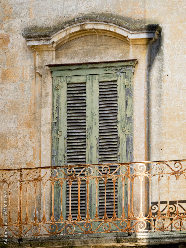Obraz premium Wrought iron balcony and old green shutters on the home in old town of Matera.