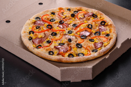 Fresh delicious pizza made in a hearth oven with olives, chili pepper and ham