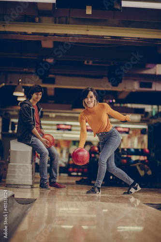 Smiling Woman throws a bowling ball.