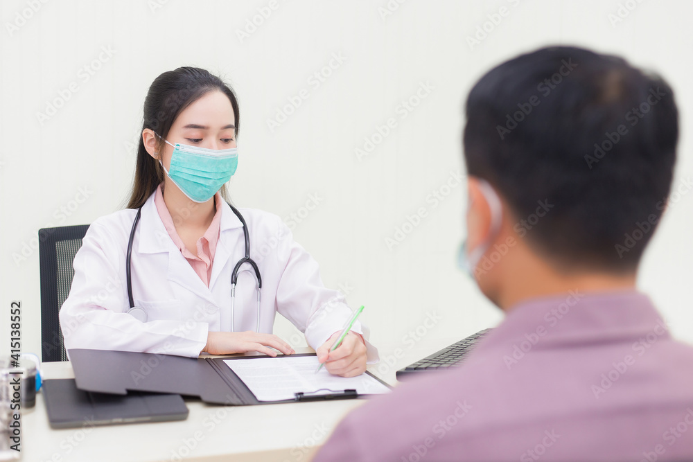 An Asian female doctor is inquiring about a male patient's illness. In the hospital examination room, she wears medical face mask to prevent Coronavirus disease in hospital. An Asian female doctor is inquiring about a male patient's illness. In the hospital examination room, she wears medical face mask to prevent Coronavirus disease in hospital.