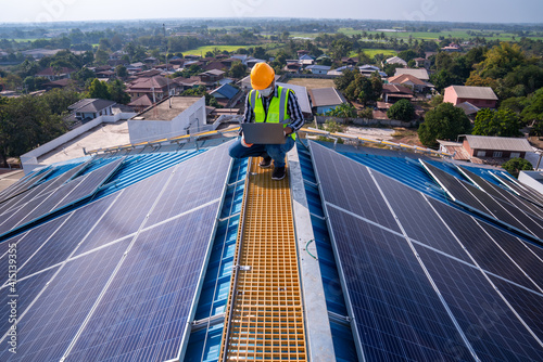 Asian technician checks the maintenance of the solar panels on the roof. photo