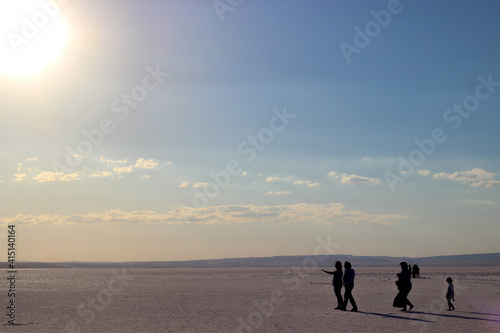 Silhouettes of people walking on Salt Lake. Bright sun and cloudy sky. Selective focus.