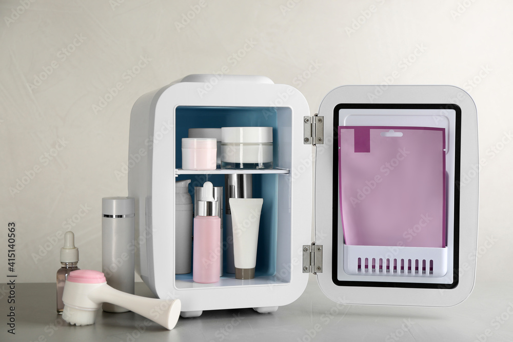Open cosmetic refrigerator and skin care products on beige background Open cosmetic refrigerator and skin care products on beige background