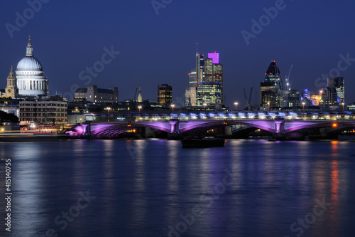 City of London skyline illuminated at night, with the River Thames