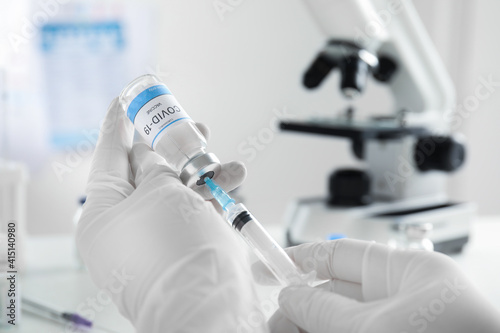 Fototapeta Naklejka Na Ścianę i Meble -  Doctor filling syringe with vaccine against Covid-19 indoors, closeup