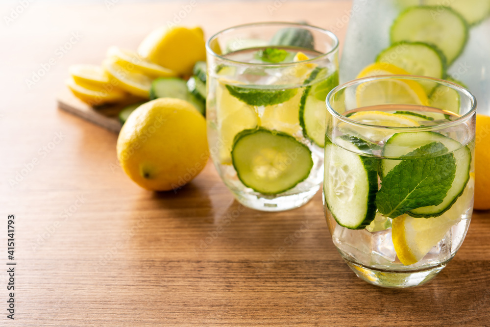 Sassy water or water with cucumber and lemon on wooden table. Copy space Sassy water or water with cucumber and lemon on wooden table. Copy space