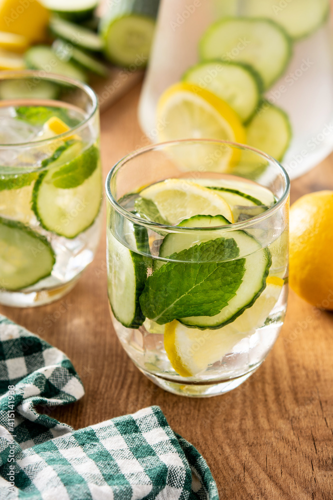 Sassy water or water with cucumber and lemon on wooden table Sassy water or water with cucumber and lemon on wooden table