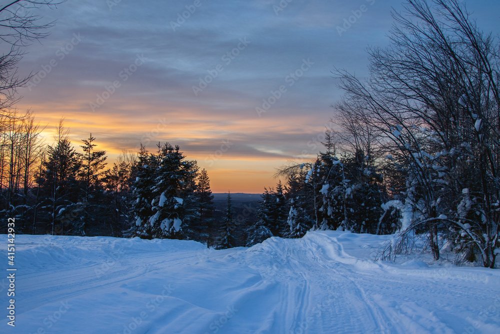 Orange sunset sky over a snowy winter forest in polar Sweden