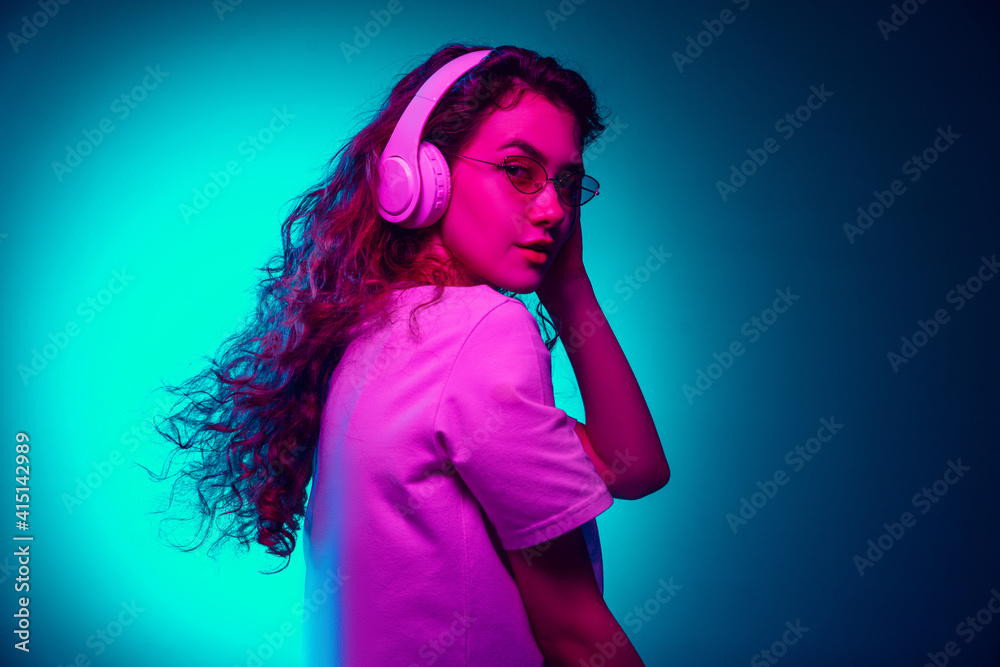 Dancing. Caucasian woman's portrait isolated on blue studio background in multicolored neon light. Beautiful female model. Concept of human emotions, facial expression, sales, ad, fashion. Copyspace. Dancing. Caucasian woman's portrait isolated on blue studio background in multicolored neon light. Beautiful female model. Concept of human emotions, facial expression, sales, ad, fashion. Copyspace.