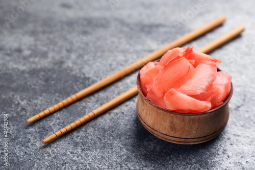 Pickled ginger in bowl and chopsticks on grey table, space for text