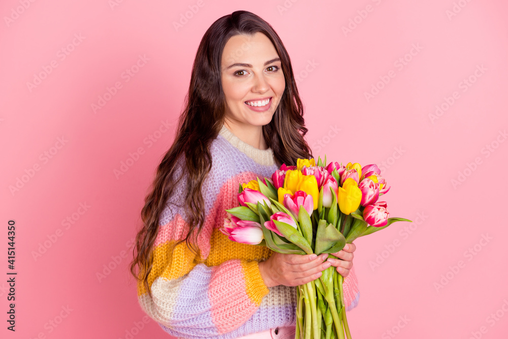 Portrait of attractive cheerful girl holding in hands bunch tulips festal event congratulate isolated over pink pastel color background