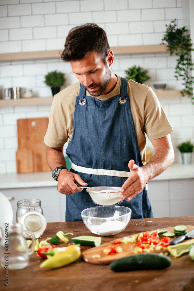 Happy man baking in the kitchen. Man making fresh pasta at home Happy man baking in the kitchen. Man making fresh pasta at home
