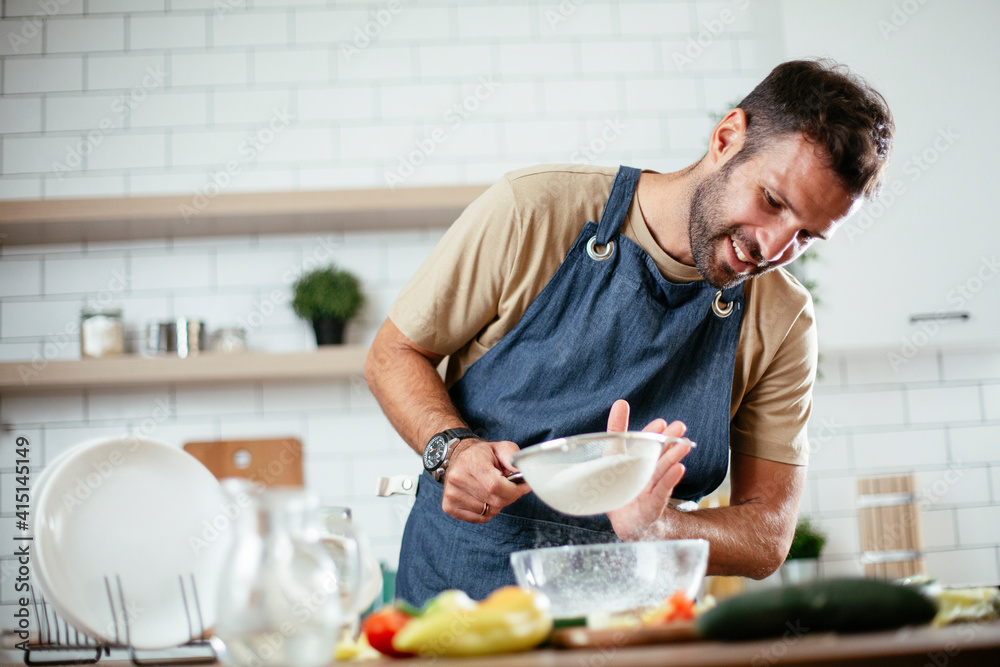 Happy man baking in the kitchen. Man making fresh pasta at home Happy man baking in the kitchen. Man making fresh pasta at home