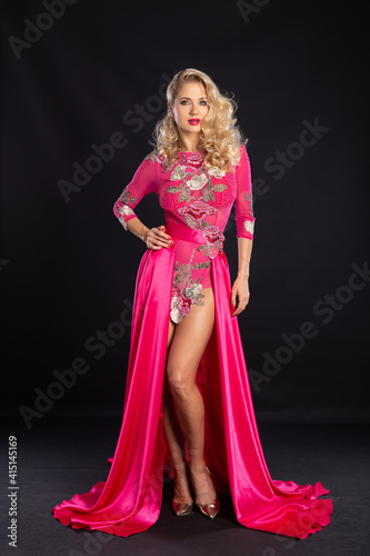Beautiful blonde in a pink sexy dress on a black background.