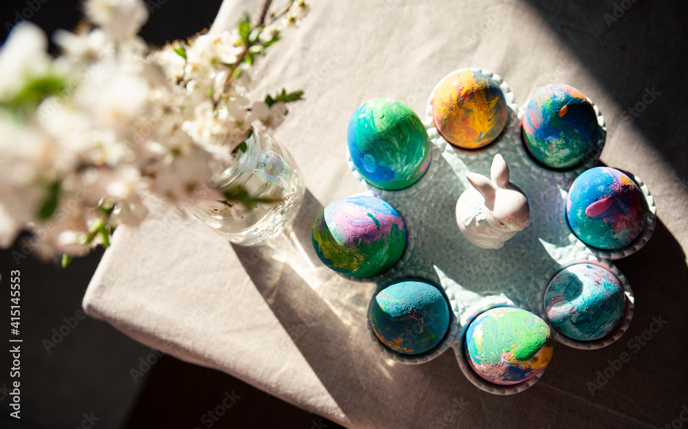 Traditional easter table with easter eggs and bunny. Colorful decoration for seasonal breakfast. White flowers in vase in spring time. Food and concept. Top view.
