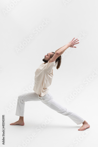 Male yoga teacher practicing in studio. Man isolated on white background doing a stretch exercises