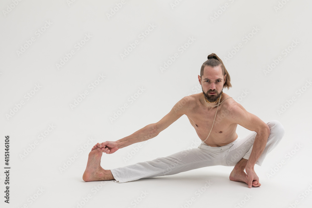 Male yoga teacher practicing in studio. Man isolated on white background doing a stretch exercises