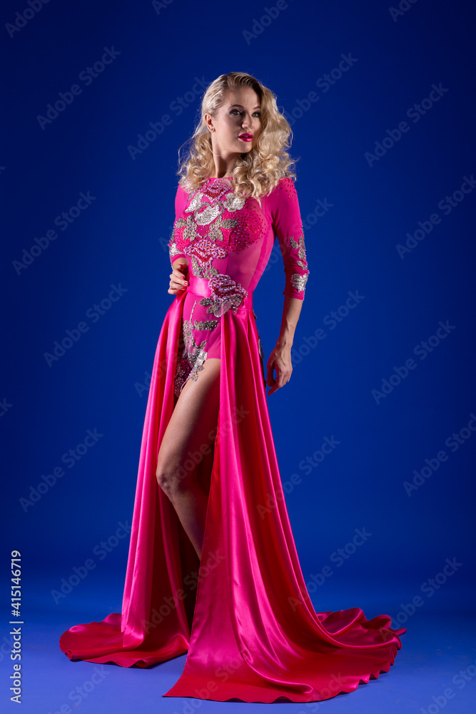 Beautiful blonde in a sexy pink dress on a blue background.
