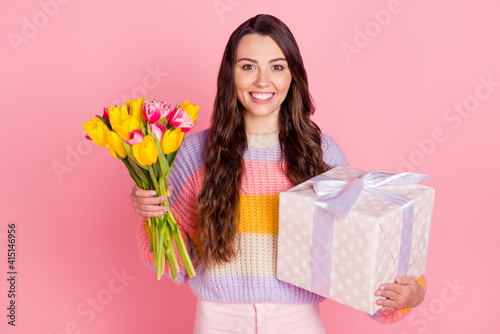 Portrait of attractive cheerful girl holding in hands tulips giftbox festal event congrats isolated over pink pastel color background