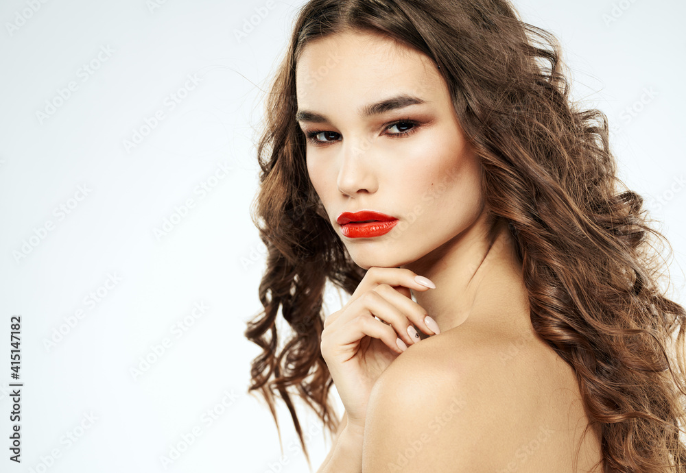 Woman with bared shoulders curly hair red lips makeup