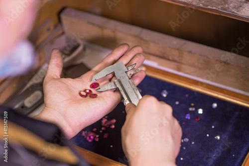 A man jeweler makes an accurate measurement of a gem using a caliper