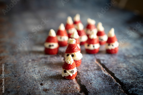 Close-up of cute strawberries shaped as Santa Claus filled with whipped cream and chocolate pieces for Christmas