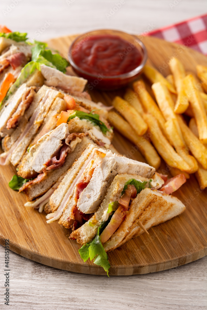 Club sandwich and French fries with ketchup sauce on wooden table Club sandwich and French fries with ketchup sauce on wooden table