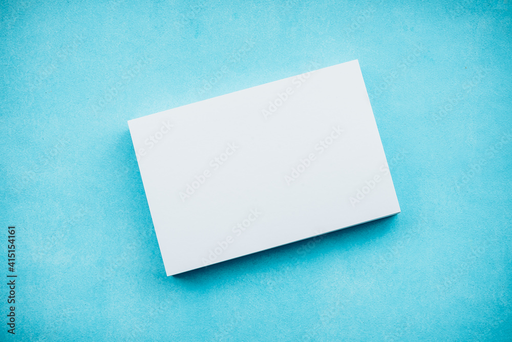 White blank cards in a stack on a blue background. A gentle romantic blank for a postcard. White blank cards in a stack on a blue background. A gentle romantic blank for a postcard.