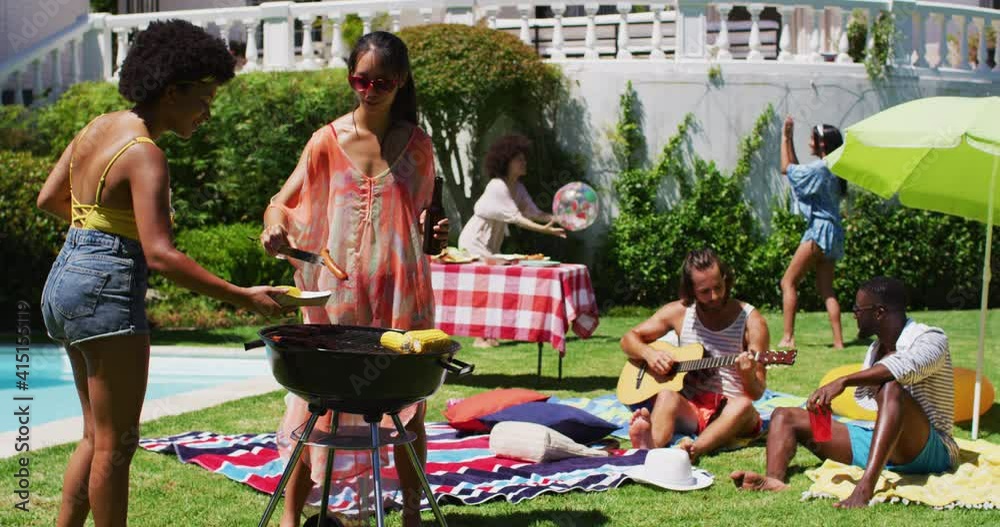 Diverse group of friends having barbecue and talking at a pool party