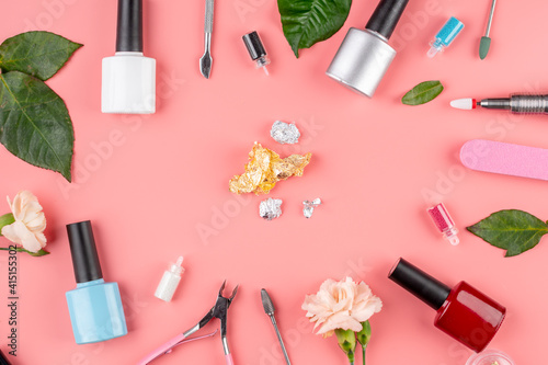 Colorful bottles of nail polishes and tools and accessories for manicure and pedicure procedures on a pink background. Top view