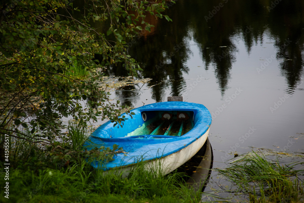 blue boat on the shore of a forest lake, selective focus