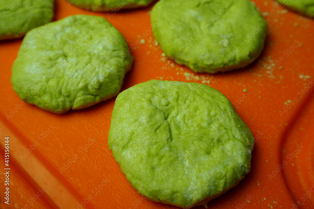 a few raw green cheesecakes with sugar-free cottage cheese in pea flour lie on a plastic orange board side view a few raw green cheesecakes with sugar-free cottage cheese in pea flour lie on a plastic orange board side view